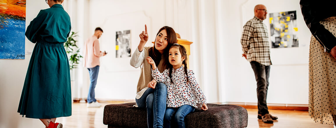 Mother and daughter admiring vibrant art pieces at a modern gallery